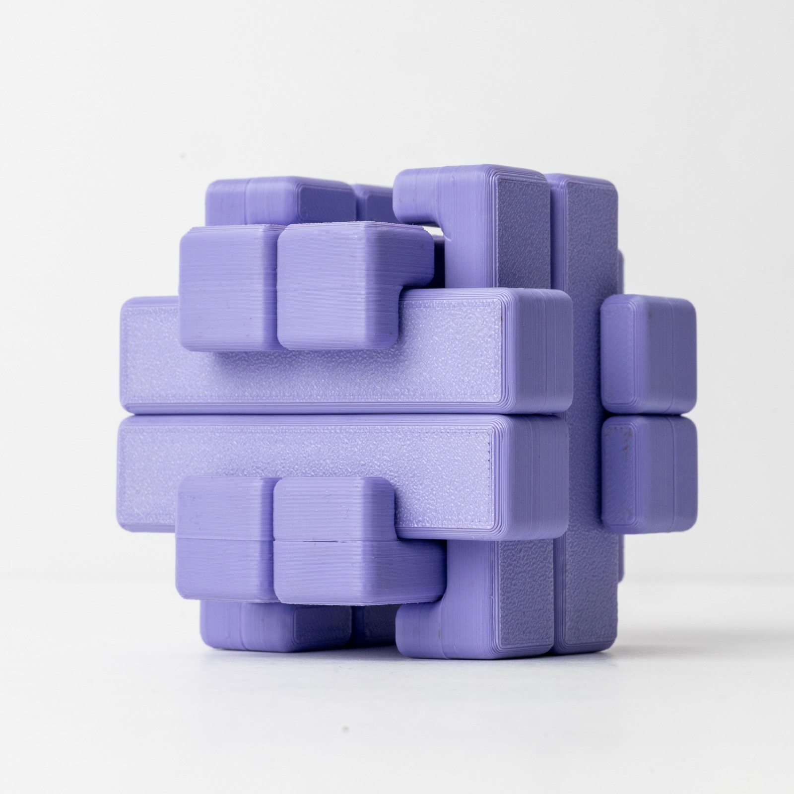 12-piece Japanese burr puzzle assembled into a geometric interlocking form, 3D-printed in natural PLA on a clean white surface.